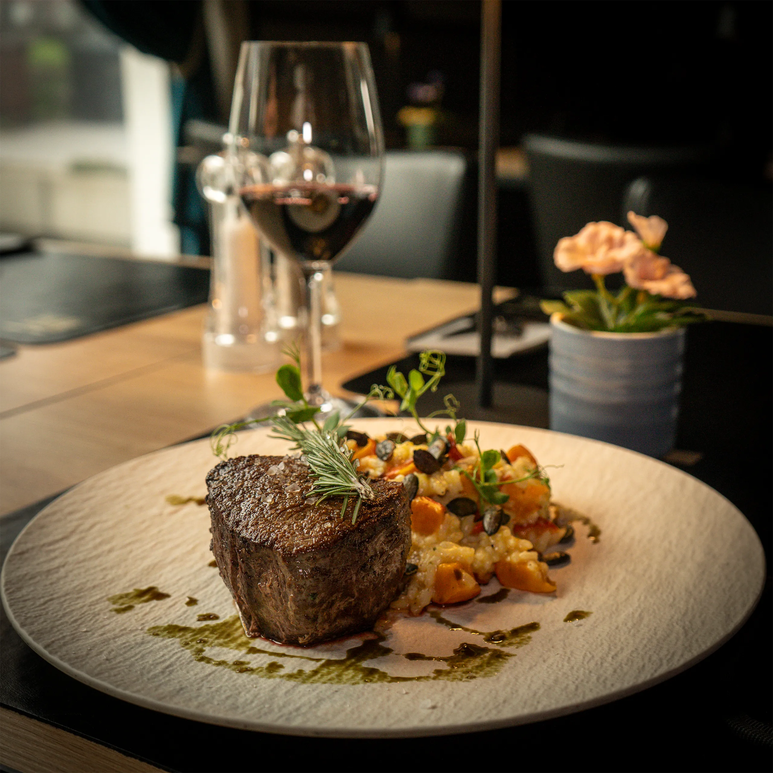 Mittagsgericht mit Steak, Beilage und Rotwein auf gedecktem Tisch_ Mittagsgericht mit Steak, Beilage und Rotwein auf gedecktem Tisch